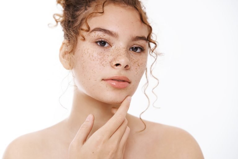 Attractive sensual gentle young redhead woman naked freckles cheeks accepting own body-positive touch skin applying skincare product, go shower, standing white background bathroom