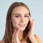 Young female smearing cream on face