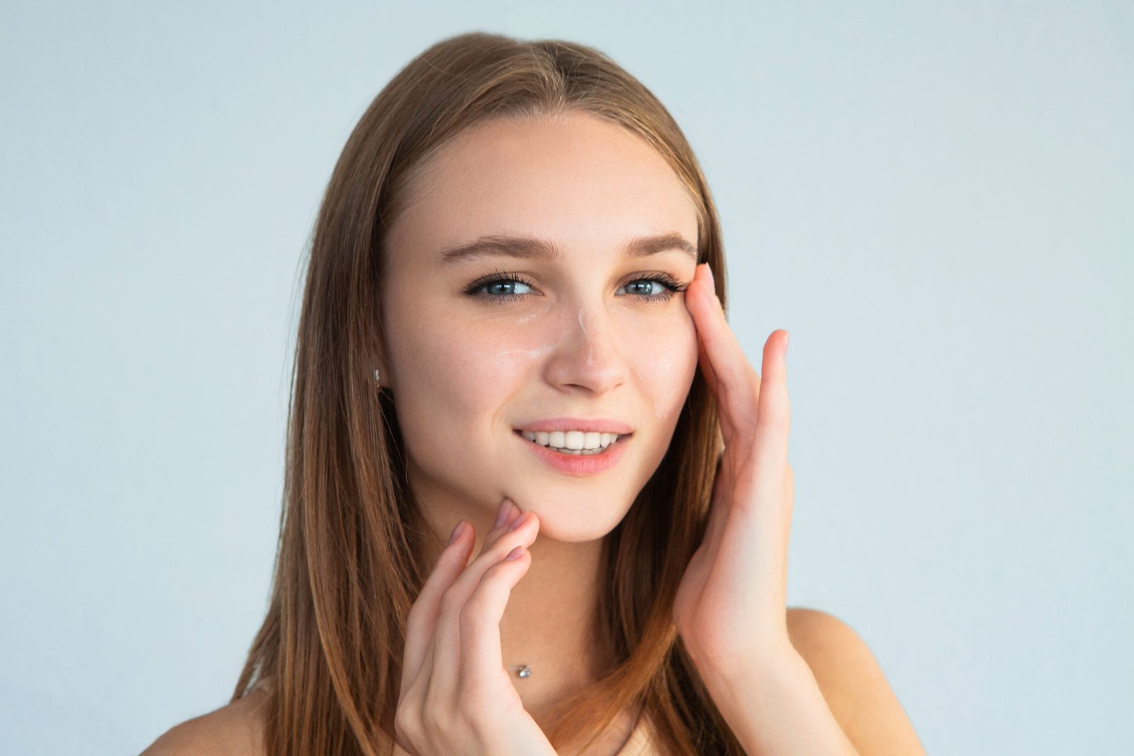 Young female smearing cream on face