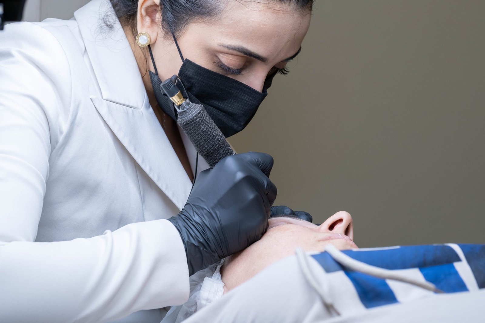 During the procedure of permanent makeup, the cosmetologist carefully designs the ideal shape for the model's eyebrows, ensuring a flawless finish